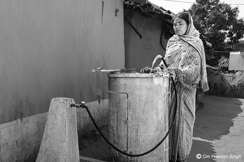 A rural woman fills her household water tank with Jal Jeevan Mission (JJM) tapwater in Seraikela-Kharsawan district, Jharkhand, India